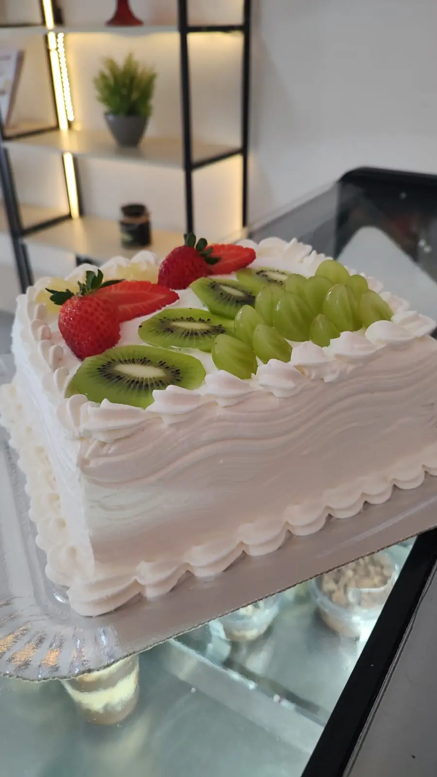 Bolo de festa branco decorado com kiwi, uva e morango